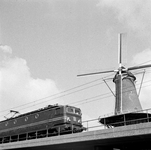 857529 Gezicht op de molen De Roos aan de Phoenixstraat te Delft, met op de voorgrond een electrische locomotief uit de ...